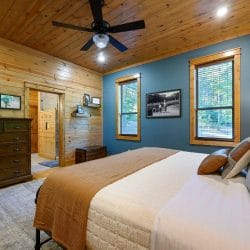 Foot of the king bed with brown and white bedding, dresser and blue-green wall