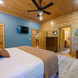 Bed with a TV on the blue-green wall and a doorway to the bathroom
