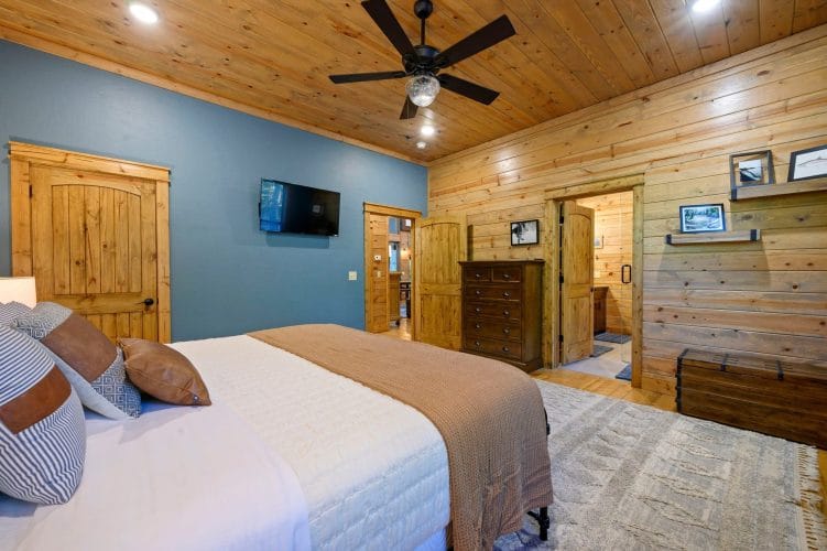 Bed with a TV on the blue-green wall and a doorway to the bathroom