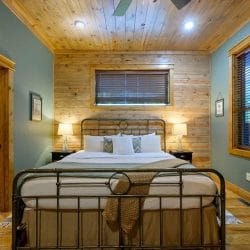 King bed with an antique-style iron frame, lamps and a bathroom doorway on the left