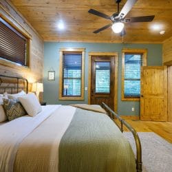 Iron bed with sage bedding and a door to the outside behind it