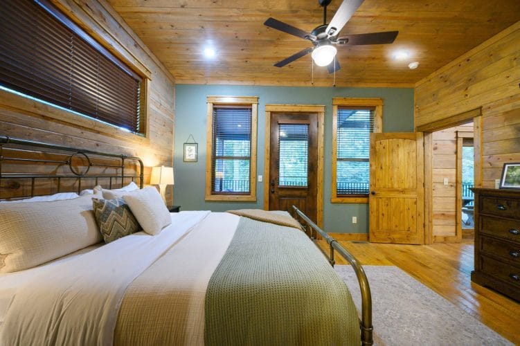 Iron bed with sage bedding and a door to the outside behind it