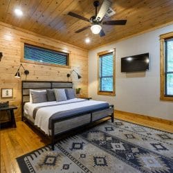 King bed with a gray and black metal frame on a patterned rug, TV on the wall