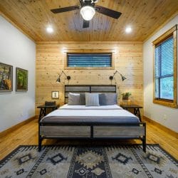 King bed with a gray metal frame and patterned rug, dresser and TV beside it