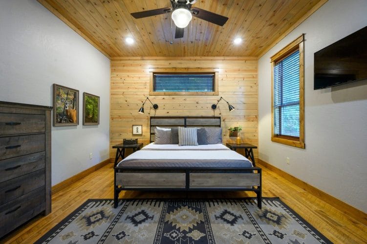 King bed with a gray metal frame and patterned rug, dresser and TV beside it