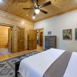 Foot of the king bed on a patterned rug with doors to the hall and bathroom behind