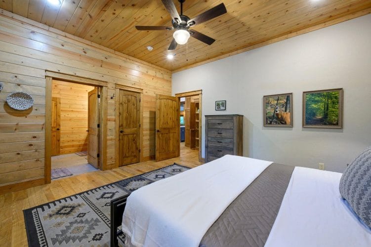 Foot of the king bed on a patterned rug with doors to the hall and bathroom behind