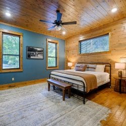 King bed with a dark metal frame and bench in a room with blue-green walls