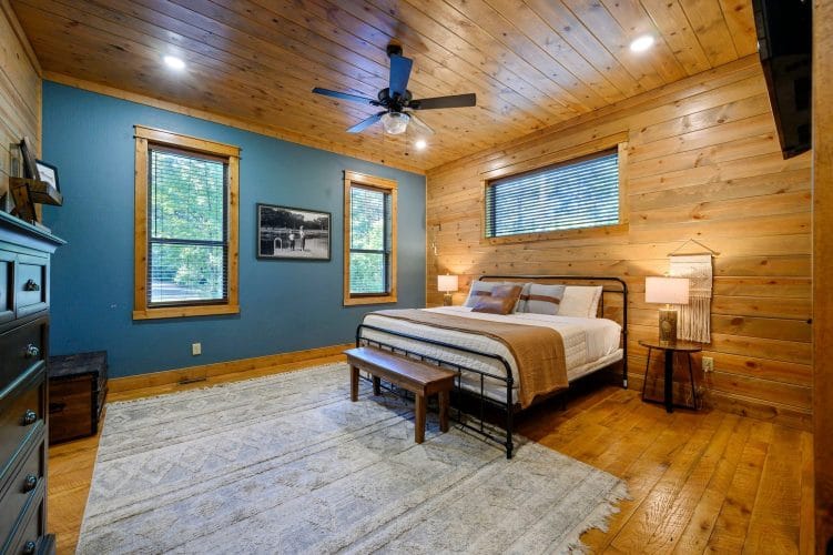 King bed with a dark metal frame and bench in a room with blue-green walls