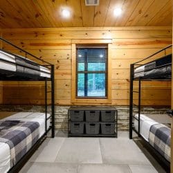 Bunk room with two sets of black metal bunk beds, plaid bedding and a window between them