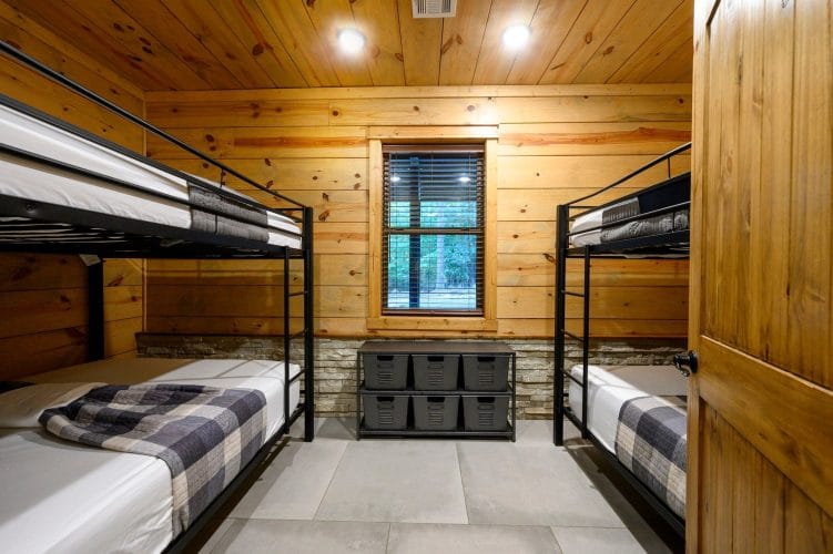 Bunk room with two sets of black metal bunk beds, plaid bedding and a window between them