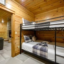 Metal bunk bed with plaid bedding and a view of the lower-level living area