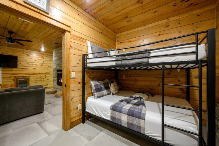 Metal bunk bed with plaid bedding and a view of the lower-level living area