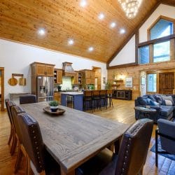 Dining table with leather chairs, kitchen and living room open behind it