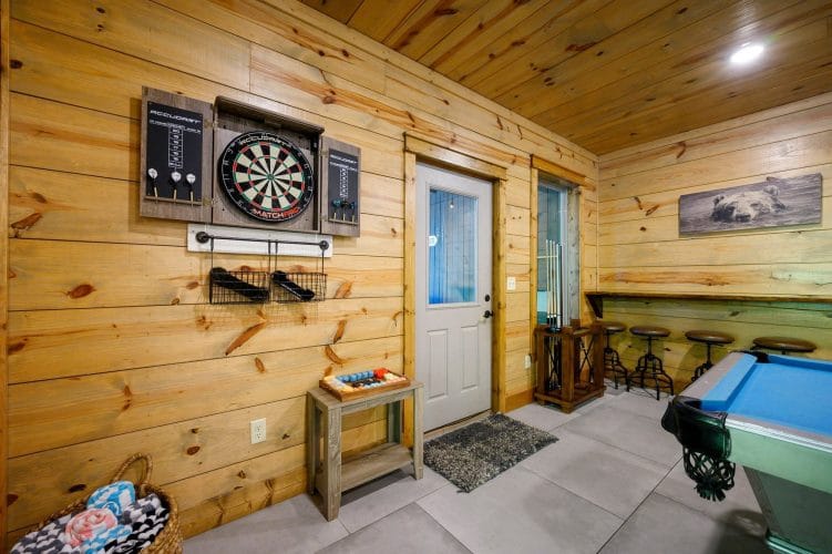 Dartboard on the wall next to an exterior door, bar stools to the right