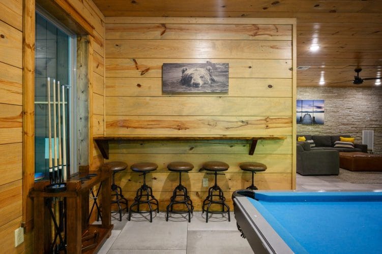 Bar-height shelf with five stools along the wall beside the pool table