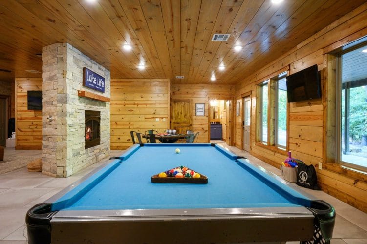 Racked pool table with the stone fireplace beyond and a TV on the wall