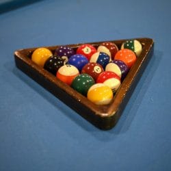 Billiard balls in a wooden rack on blue felt