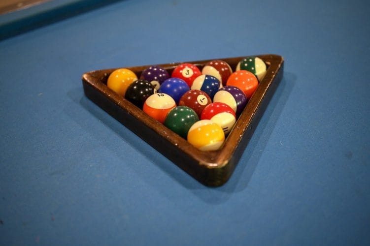 Billiard balls in a wooden rack on blue felt