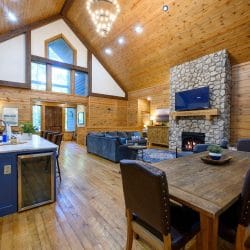 Navy kitchen island with a wine fridge, with the dining table and fireplace beyond