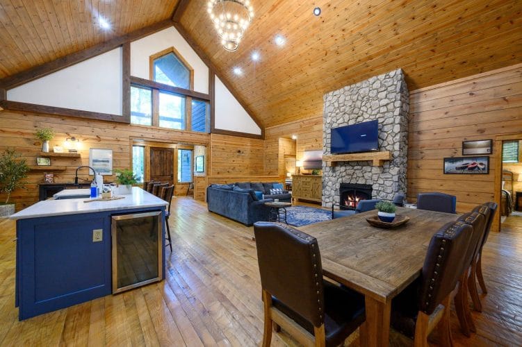Navy kitchen island with a wine fridge, with the dining table and fireplace beyond