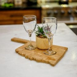 Two wine glasses and a small plant on a cutting board on the kitchen counter
