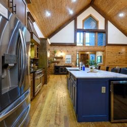 Stainless fridge and navy island with the great room behind