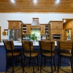 Navy island with four wood counter stools and the kitchen behind