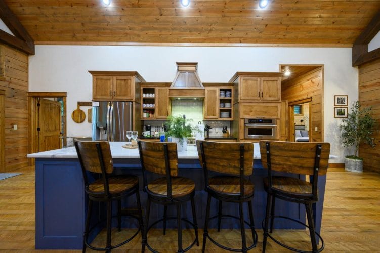 Navy island with four wood counter stools and the kitchen behind