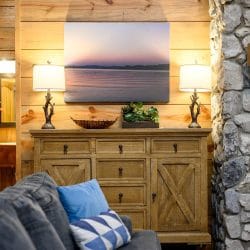 Wood sideboard under a framed lake photo, beside the stone fireplace