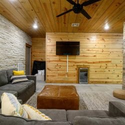 Gray sectional and ottoman facing the TV in the lower-level living area