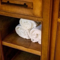 Rolled white towels on a shelf inside a cabinet