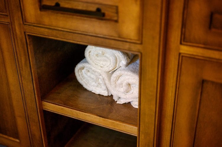 Rolled white towels on a shelf inside a cabinet