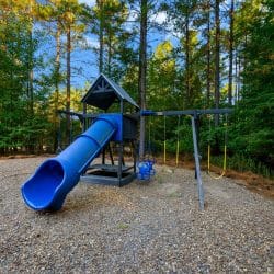 Playset with a blue slide and swings on a gravel play area
