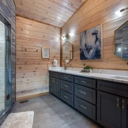 Bathroom with a navy double vanity, a mirror over each sink and a glass walk-in shower