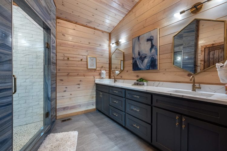 Bathroom with a navy double vanity, a mirror over each sink and a glass walk-in shower