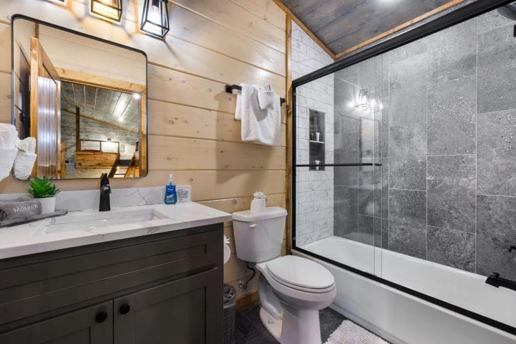 Bathroom with a tub-and-shower and gray tile wall