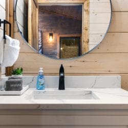 White vanity with a round mirror, the bedroom reflected behind