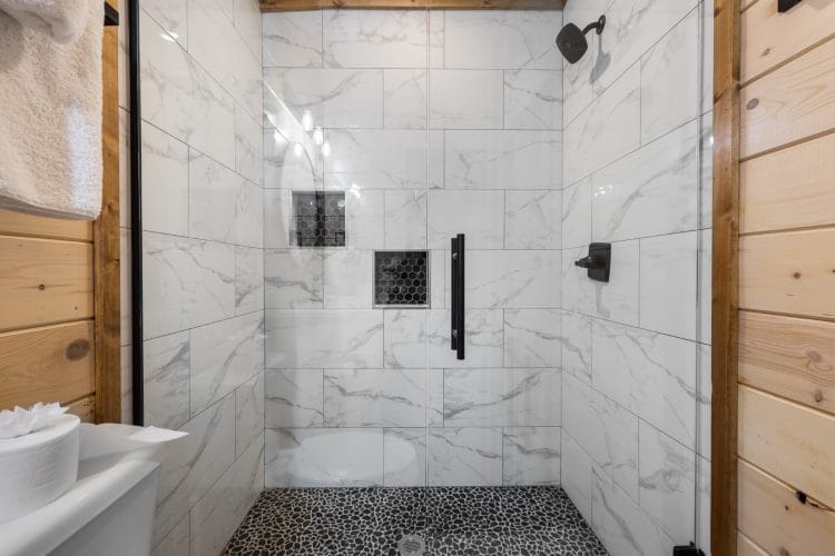 Marble-look tiled walk-in shower with a black rain head