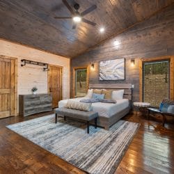 Game house king bedroom with a pine plank ceiling, a ceiling fan and a blue-and-white rug