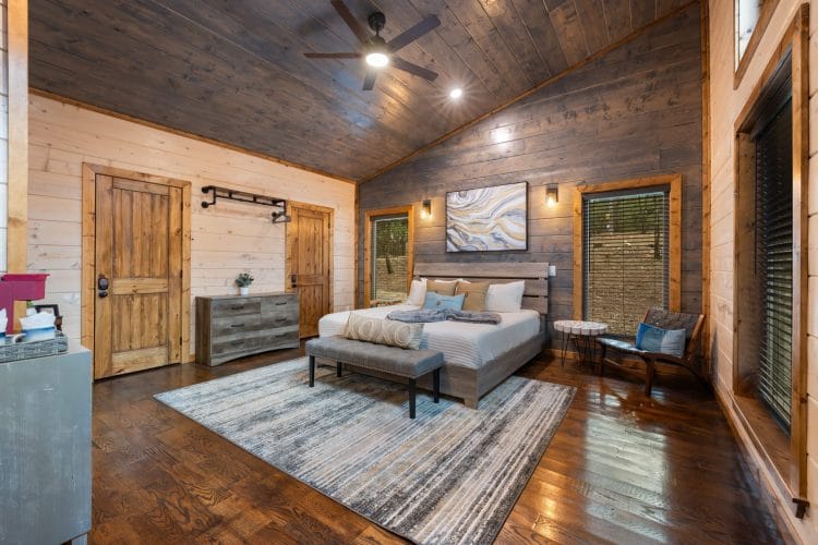 Game house king bedroom with a pine plank ceiling, a ceiling fan and a blue-and-white rug