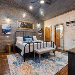 Game house second king bedroom with a black iron bed and an upholstered bench