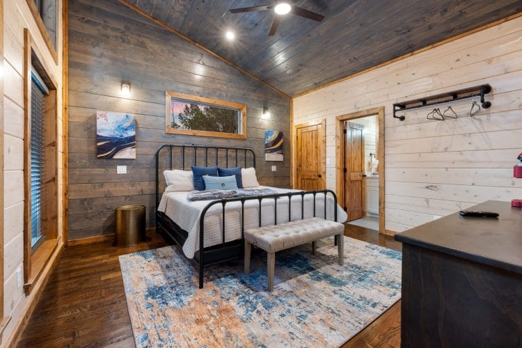 Game house second king bedroom with a black iron bed and an upholstered bench