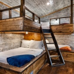 Closer view of the built-in bunk with a ladder and navy bedding