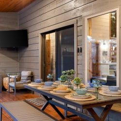 Outdoor dining table set with bowls and plates on the covered deck
