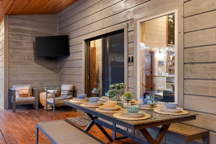 Outdoor dining table set with bowls and plates on the covered deck