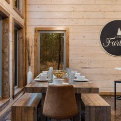 Dining table with benches and a round wall sign, with the kitchen island behind