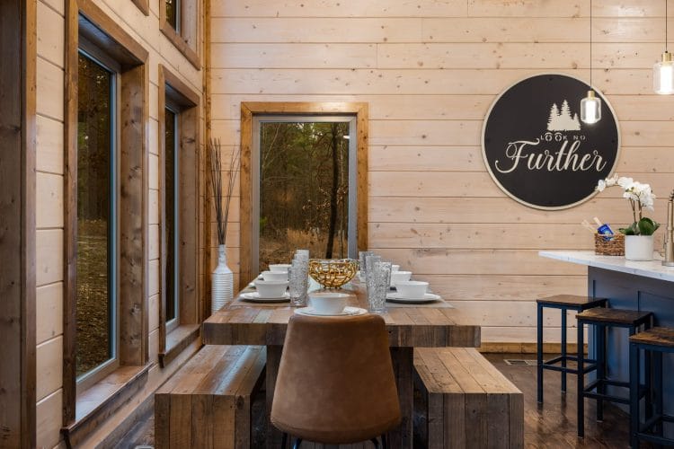 Dining table with benches and a round wall sign, with the kitchen island behind
