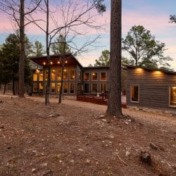 Back view of the cabin with large windows and soffit lights at dusk