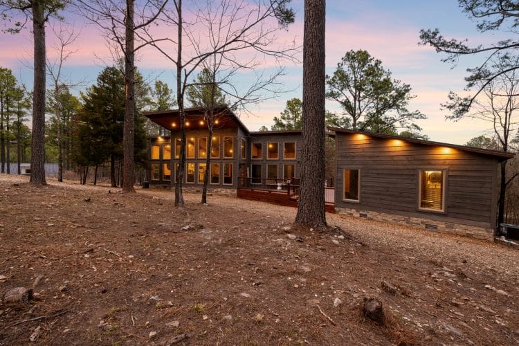 Back view of the cabin with large windows and soffit lights at dusk